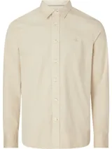 Camisa de manga larga color beige confeccionada en popelina de algodón, con cierre frontal con botones, puños con botones y logo Calvin Klein bordado en el pecho.