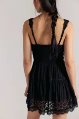 Mini vestido slip negro de tela liviana y fruncida, con escote corazón, cierre delantero regulable de gancho, tiras regulables y encaje translúcido en los bordes y el ruedo. Silueta entallada en la parte superior y con vuelo en la falda.