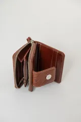 Billetera de cuero con textura tipo cocodrilo, color marrón, con cierre perimetral y solapa frontal con broche a presión metálico. Incluye una correa de muñeca desmontable.