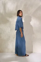 Pantalón de denim negro de tiro medio, corte wide leg con pierna muy ancha y caída fluida. Presenta un detalle de presilla metálica decorativa en la cintura.