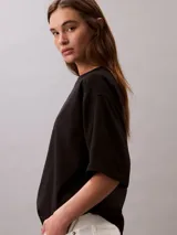 Remera de corte oversize confeccionada en algodón, con cuello redondo y mangas cortas. Presenta un estampado frontal con el logo de la marca en disposición vertical.