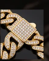 Pulsera tipo cadena cubana de acero con baño de oro, adornada con engarces de micropave de circonias en cada eslabón y en el cierre central.