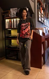 Remera de manga corta con cuello redondo y calce oversize, color negro con efecto lavado. Presenta un estampado frontal gráfico con motivos musicales y tipografía en tonos rojos y blancos.