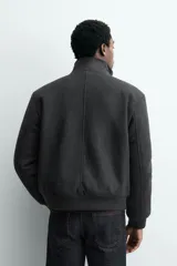 Cazadora bomber de corte regular con forro interior de tejido efecto pelo. Presenta cuello subido, cierre frontal con cremallera metálica, bolsillos laterales de vivo y acabados en rib en puños y cintura.