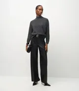 Suéter de punto gris con cuello medio estructurado y mangas largas. Presenta un diseño con aplicación de pequeñas cuentas decorativas distribuidas por el frente.