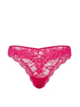 Tanga de encaje color fucsia, con tiro bajo y detalle de pequeña roseta decorativa en el centro.