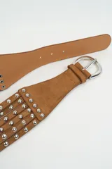 Cinturón de gamuza color tostado con diseño de tiras múltiples decoradas con tachas metálicas plateadas y hebilla metálica.