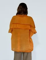 Camisa amarilla con cuello mao, mangas cortas y volados en el pecho.