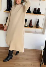 Vestido midi color beige de tejido acanalado, con cuello alto y mangas largas.