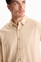 Camisa de lino de manga larga, color beige, con cuello clásico y cierre frontal de botones.
