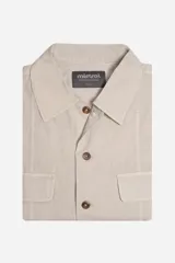 Camisa de manga corta color beige, de corte recto y holgado, con cuello clásico y cierre frontal con botones. Presenta dos bolsillos de parche en el pecho.