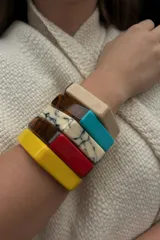 Pulsera rígida de forma hexagonal confeccionada en resina, con secciones en colores rojo, ámbar y efecto mármol blanco.
