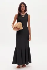 Vestido largo de lino marrón, sin mangas, con cuello a la base y canesú en la espalda. Cuenta con godets en el ruedo que le aportan movimiento y amplitud.