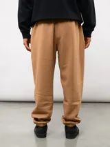 Pantalón jogger de felpa color negro, con cintura elástica, puños en los tobillos y etiqueta con el logo de la marca en la parte frontal.