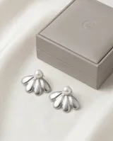 Caravanas de acero con diseño de pétalos plateados y una perla central.