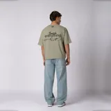 Remera boxy de calce corto y ancho, color verde oliva, con cuello redondo, mangas cortas y estampa frontal minimalista con texto y logo.