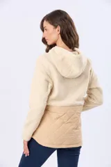 Campera beige con capucha y cordones ajustables, combinada en su parte superior con tejido de corderito y en su parte inferior con diseño capitoné. Cuenta con cierre frontal y broches a presión, además de bolsillos laterales.