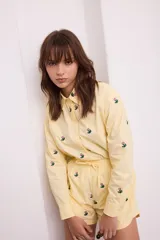 Camisa negra de algodón con bordados de pequeñas flores rosas. Presenta cuello clásico, cierre frontal con botones y mangas largas.