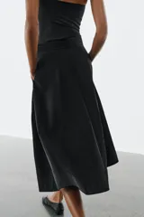 Falda midi de tiro alto en color negro, con diseño en línea evasé y cierre de cremallera oculta en la costura.