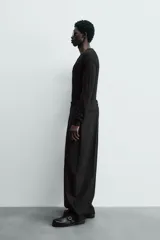 Jersey negro de punto fino, con cuello pico profundo y mangas largas. Terminaciones acanaladas.