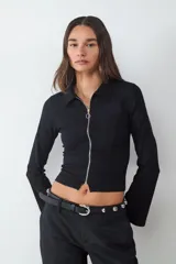 Campera de manga larga confeccionada en tejido crepé, con cuello camisero y cierre frontal metálico completo. Presenta un diseño entallado y moderno con mangas ligeramente acampanadas.