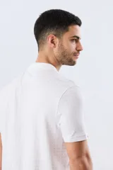 Remera polo de piqué manga corta, color blanco con estampado geométrico sutil. Presenta cuello camisero y cartera con dos botones oscuros.