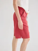 Short de lino color rojo, de tiro medio, con cierre frontal y bolsillos laterales. Presenta un diseño clásico y versátil.