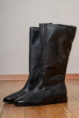 Bota alta de cuero negro con caña calada, tacón bajo y cierre lateral.