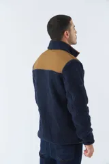 Campera de sherpa para hombre, color azul marino con detalles en marrón. Tiene cuello alto, cierre frontal y bolsillos laterales con cierre.