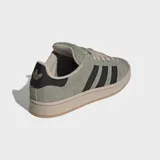 Championes Adidas modelo Campus 00s, con diseño inspirado en los años 80. Presentan una parte superior de gamuza texturizada en color verde oliva, con las icónicas tres rayas laterales en negro y detalle en el talón. Cuentan con cordones anchos y suela de goma en tono beige.