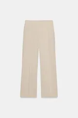 Pantalón de tiro medio confeccionado en lino color beige, de pernera recta con nervios marcados en el delantero. Posee bolsillos frontales, falsos bolsillos de vivo en la espalda y cierre frontal con cremallera, botón interior y gancho.