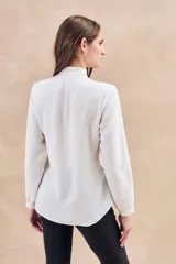 Blusa negra con cuello mao, calce al cuerpo y mangas 3/4 con puños abotonados. Cierre frontal con botones.