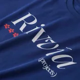 Remera azul con estampa frontal de la marca Rivvia en color blanco y tres flores rojas.