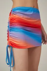 Minifalda con estampado degradado en tonos azul, lila, naranja y rojo. Presenta frunces laterales con cordones ajustables.