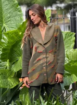 Saco de lana color verde militar con estampado abstracto en tonos verde oliva y detalles bordados en rojo. Tiene cuello solapa, cierre frontal con botones de madera y puños acanalados.