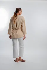 Blusa de manga larga color beige, de estilo cruzado con lazo lateral para atar y escote en V.