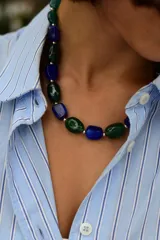 Collar de cuentas de resina en forma de piedras pulidas, alternando colores azul y verde, con pequeñas esferas metálicas entre ellas.