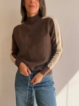 Sweater de punto con cuello alto, diseño bicolor en tonos marrón y beige, con franjas laterales en las mangas y costura central vertical.
