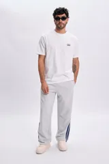 Pantalon deportivo gris melange de corte holgado, con franjas laterales en color azul marino.