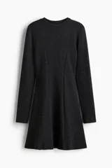 Vestido mini de manga larga confeccionado en punto fino, con cuello redondo y costuras decorativas frontales que definen la silueta. Presenta una falda con vuelo y pinzas en la espalda.
