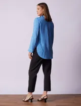 Camisa celeste con rayas verticales blancas, de corte clásico, cuello a la base, escote en V y abertura central con botones.