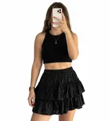 Pollera short negra con estampado de lunares blancos, tiro alto, cintura elástica y diseño de volados escalonados.