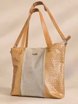 Cartera tipo tote de cuero color tostado con textura símil cocodrilo en los laterales y panel central texturizado en tono beige, con aplique metálico de la marca. Cuenta con doble asa de hombro y correa larga ajustable.