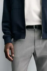 Pantalón de corte slim fit confeccionado en tejido elástico, con cintura elástica, cierre frontal con cremallera y botón, bolsillos laterales y bolsillos traseros de vivo.