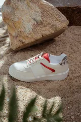 Zapatillas bajas de cuero color blanco hueso con detalles en rojo y estampado animal print en el talón.