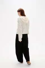 Sweater de punto a rayas horizontales color marrón y blanco, con cuello en V, capucha con cordones y cierre frontal parcial con botones. Presenta un diseño de manga larga con caída de hombros.