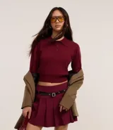 Suéter corto de punto color borgoña con cuello polo y botones en la vista.