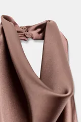 Top blanco satinado con cuello halter y escote fluido. Cierre en la espalda con botones.