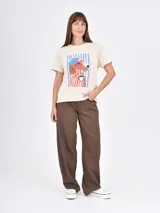 Remera lila de corte recto y mangas cortas, con estampado pequeño de un gato blanco con gorro rojo, gafas de sol y copa de vino, junto a la frase 'J'adore'.