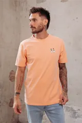 Remera color durazno de corte recto y manga corta, con cuello redondo y pequeño bordado de dos patos en el pecho.